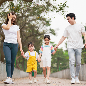 A young Asian single mom and man walk with two young children.