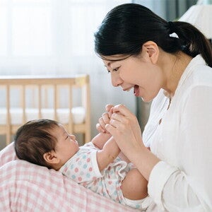 A young Asian woman sings a Filipino nursery rhyme or lullaby to a baby lying on her lap.