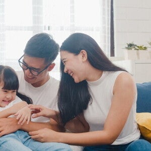 An Asian couple with their little girl on the sofa at home, a picture of family love.