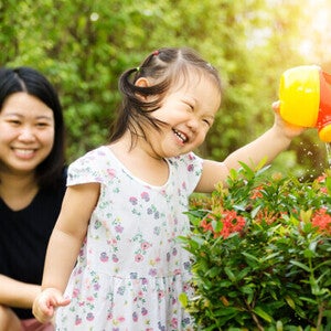 Asian mother and child water plants together happily.