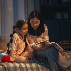 Asian mom and daughter reading a book at night as a daily routine.