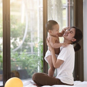asian-mom-holding-baby-while-seated-on-floor