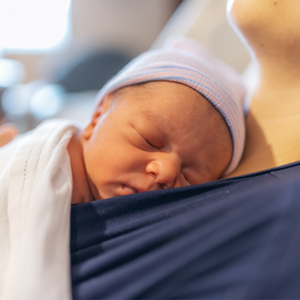 A mom holding her premature baby in the hospital, doing kangaroo mother care for skin-to-skin contact.