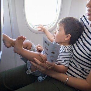 Asian mom traveling with baby on her lap in the plane.