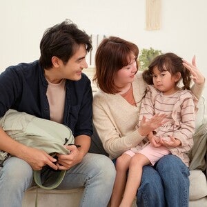 Asian parents at home in the living room talking to their child with social anxiety who doesn’t want to go to school.