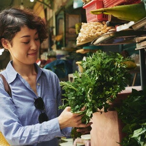 Asian woman buying vegetables at the wet market and thinking of budget ulam ideas to fit ₱500 