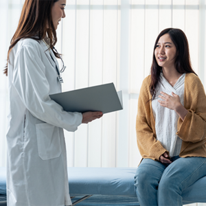 Young Asian woman talking to her doctor about her pregnancy spotting color and flow.