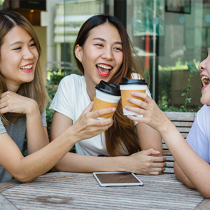 Happy Asian women friends sitting in a cafe, drinking coffee and talking together as a support system.