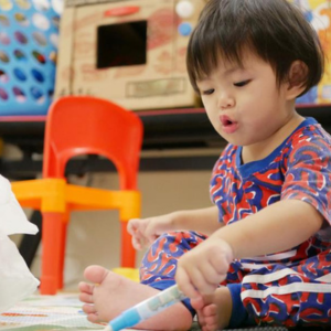 Asian 18-month-old baby scribbles with a pen during playtime.