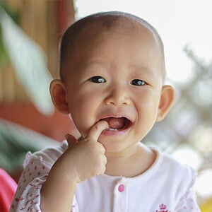 Asian baby with one of their fingers in their mouth. Asian baby with one of their fingers in their mouth.