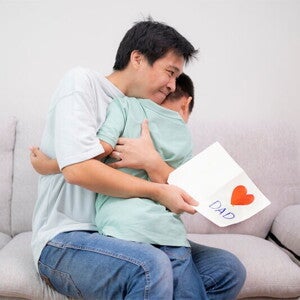 Asian dad hugs son after receiving a Father's Day card Asian dad hugs son after receiving a Father's Day card
