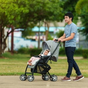 Asian dad pushes his baby's stroller through a park