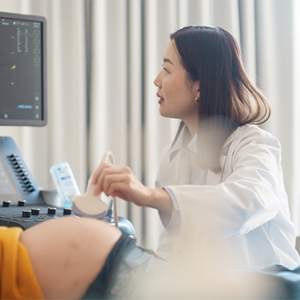 Asian doctor performs one of the types of ultrasounds in pregnancy.