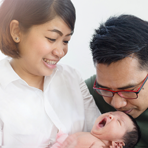 Asian mom and dad holding their newborn baby, thinking of baby boy names with meaning
