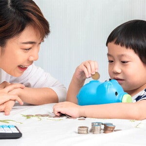 Asian mom and son putting coins in piggy bank Asian mom and son putting coins in piggy bank