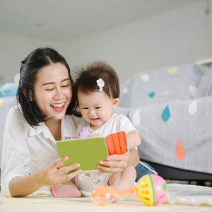 Asian mom and toddler daughter happily reading