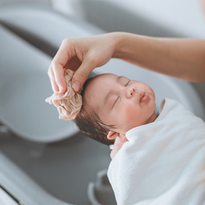 Asian mom washing newborn child in their baby bath. Asian mom washing newborn child in their baby bath.