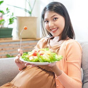 Asian pregnant woman holds a plate of vegetable salad for her dailly vitamin intake. Asian pregnant woman holds a plate of vegetable salad for her dailly vitamin intake.