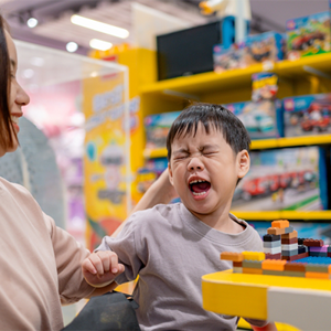 Asian toddler becomes short-tempered while in a toy store with mom Asian toddler becomes short-tempered while in a toy store with mom
