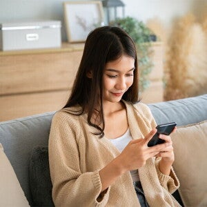 Asian woman looking at her phone's calendar to check her ovulation days Asian woman looking at her phone's calendar to check her ovulation days.