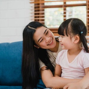 Asian woman sits her child on her lap and looks at her lovingly after she had to discipline her
