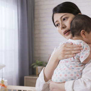 Asian young woman burps her baby over her shoulder after feeding. 