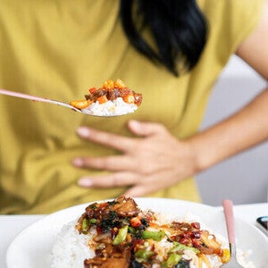 Close-up pic of an Asian woman’s hand holding a spoon of spicy food for pregnant women.