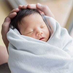 Closeup of healthy newborn in a swaddle being held by the father. Closeup of healthy newborn in a swaddle being held by the father
