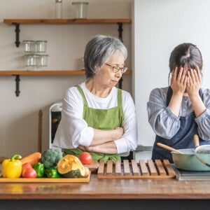 Elderly Asian woman berating a younger woman to tears in the kitchen.