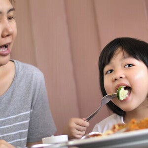 Filipino mother with daughter eating together at home for healthy weight gain.