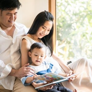 Filipino toddler reading a storybook in Tagalog with his parents.