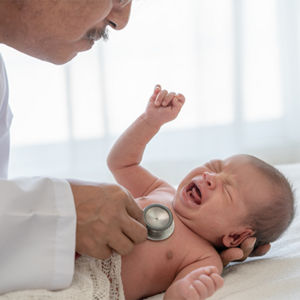 Photo of a doctor examining a newborn in the hospital with a stethoscope.