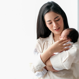 Photo of Asian mom carrying her infant upright to help with newborn hiccups