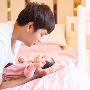 Young Filipino dad talks to his newborn while putting them down.