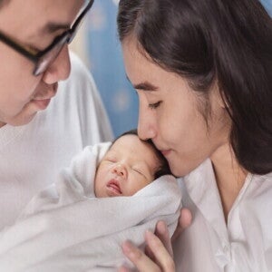 Asian newborn baby yawns as they lie in a bassinet at a maternity hospital.