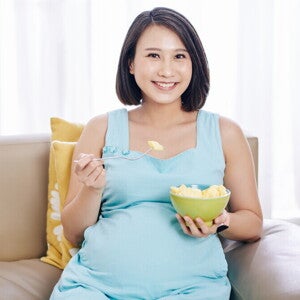 Teaser_Image Young and smiling Asian pregnant woman eat a bowl of fruits good for pregnancy.