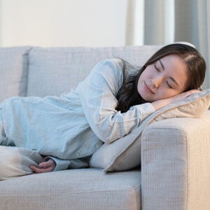 Recognizing Early Signs of Pregnancy Young Asian woman falls asleep on the sofa, exhibiting an early sign of pregnancy.