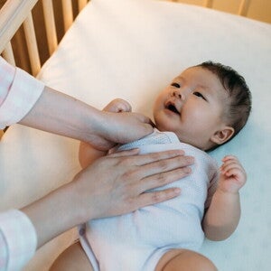 Baby Sleeping Position Basics Asian baby being put to sleep on their back in safe crib.