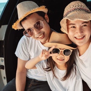 A young Asian couple and their preschooler daughter on a beach for a family trip out of town.