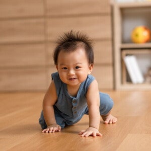Healthy Asian baby crawl on their hands and knees on wooden floor.
