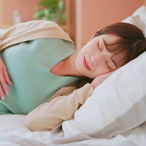 Young Asian mom at Week 20 of pregnancy sound asleep in bed.