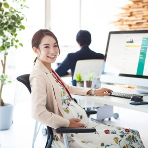 Pregnant Asian takes a break from working on her computer at an office.