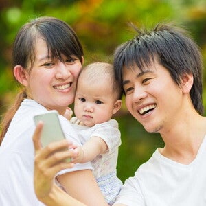 8 Meaningful Baby Monthly Milestone Ideas Asian couple takes a selfie with their baby.