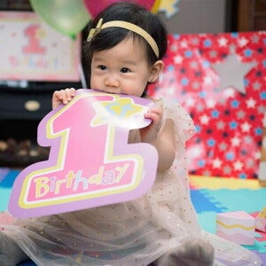 Little Asian baby girl celebrating her first birthday with a birthday party. 
