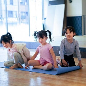 Three Adorable Asian preschoolers with healthy tummies sit on a yoga mat in fitness studio Three Adorable Asian preschoolers with healthy tummies sit on a yoga mat in fitness studio