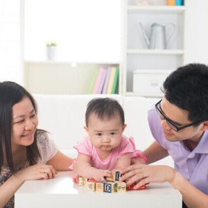 Young Asian parents spending quality time and playing with their little girl in the living room.