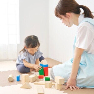A little Asian girl and her green flag yaya playing with building blocks at home.