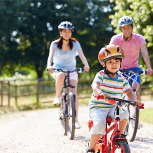 Young Asian family of three go biking at a park to prevent child obesity. Young Asian family of three go biking at a park to prevent child obesity.
