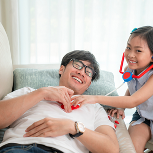 Young Asian girl listens to her father's heartbeat with a toy stethoscope, pretending to do dad’s medical checkups Young Asian girl listens to her father's heartbeat with a toy stethoscope, pretending to do dad’s medical checkups