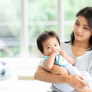 Young Asian mom carrying her baby and thinking about how to increase breast milk supply.